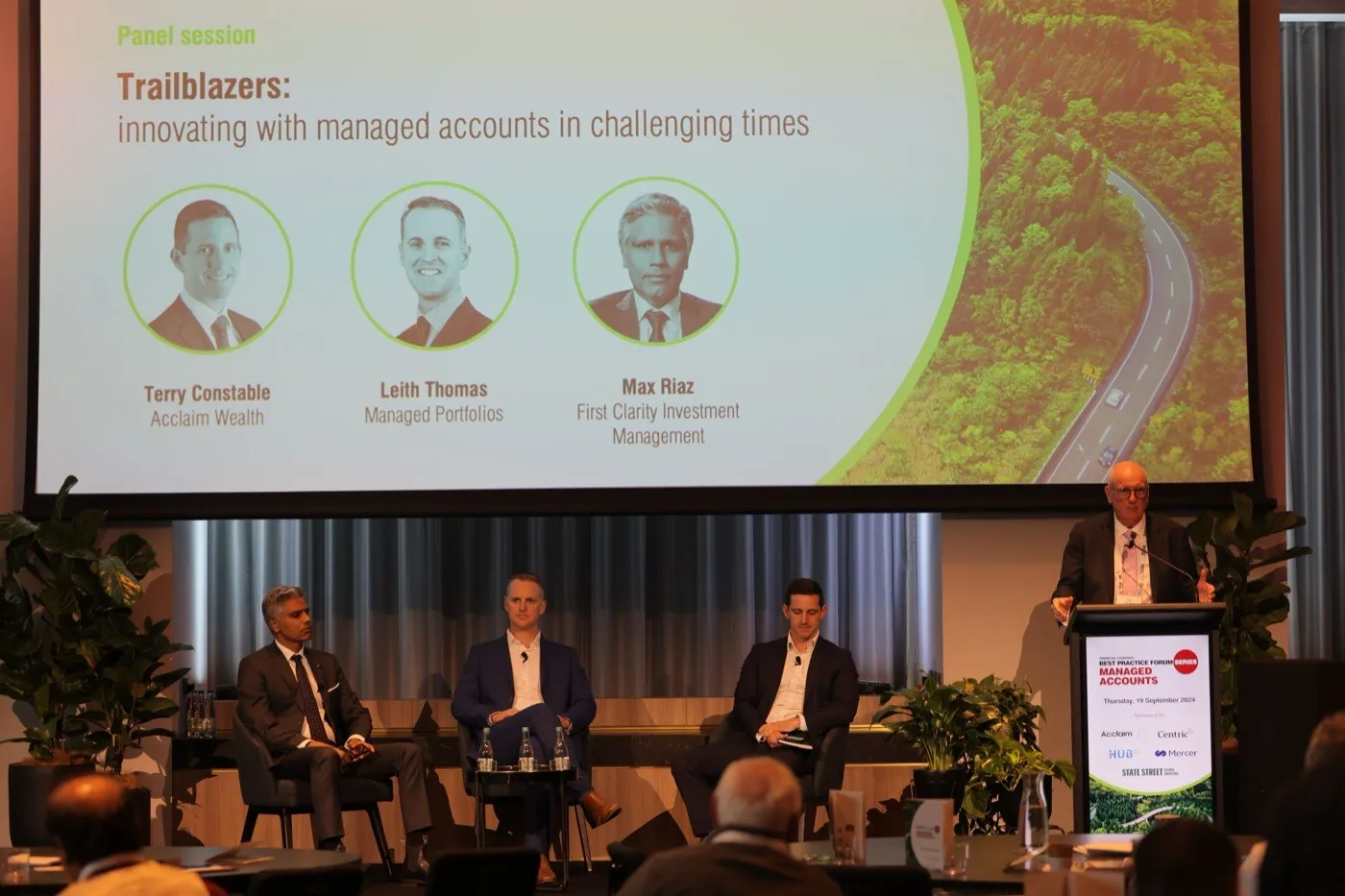Leith Thomas on stage with two other panellists, beneath a screen reading "Trailblazers: innovating with managed accounts in challenging times".
